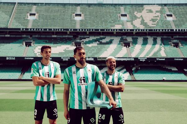 Real Betis players Edgar González (left), Aitor Ruibal (right) and Borja Iglesias holding a stadium seat made with fishing nets recovered from seas and ports by Gravity Wave. ©Gravity Wave
